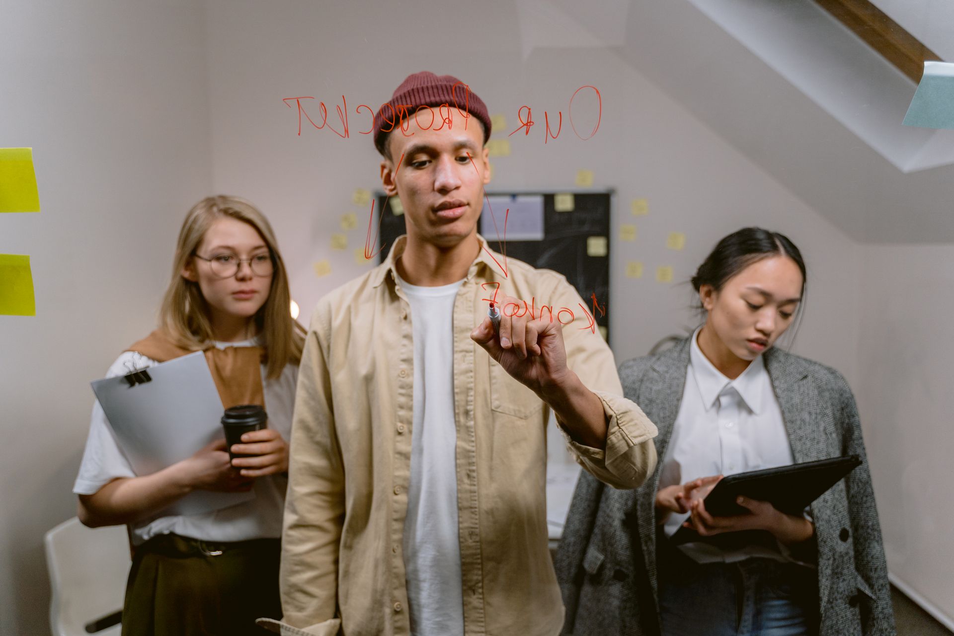 A team discusses a project at a glass board